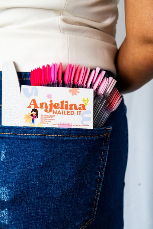 The Anjelina Nailed It card and a fan of nail tips in AJ's pocket